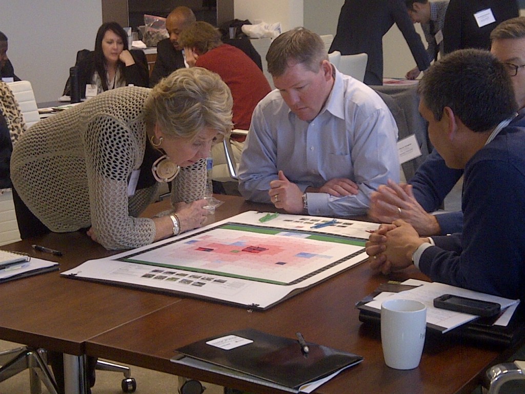 Sheila Ogle of Ogle Enterprises (Raleigh), left, Shane Douglas of Collier International (Nashville) and Juan Gonzalez of KeyBank Indiana (Indy) go through an exercise led by Jarrett Walker (@humantransit) where teams design a transit network for a fictional city with a set budget — one way to experience the real-life trade-offs that transit planners and cities have to make.